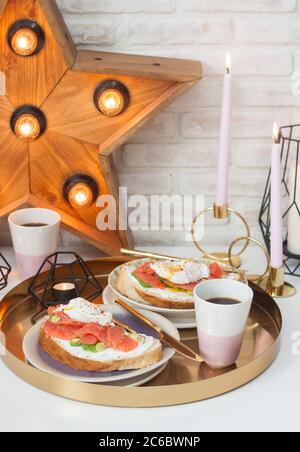 Toasts with cream cheese, smoked salmon, avocado and poached egg. Cup of coffee. Stock Photo