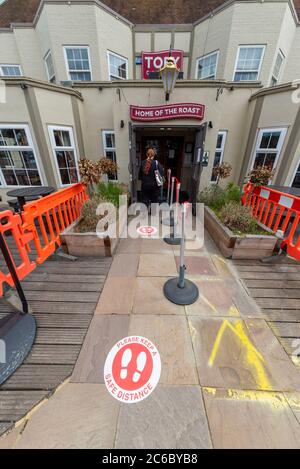 Female entering a Toby Carvery restaurant with COVID-19 Coronavirus safety measures in place after lockdown easing. Hospitality business re-opening Stock Photo