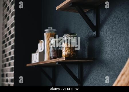 Pasta and grocery in glass jars on a wooden shelf in the kitchen. Detail Stock Photo