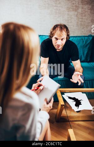 A woman psychologist consults with a male patient - on the table are tablets with a Rorschach test Stock Photo