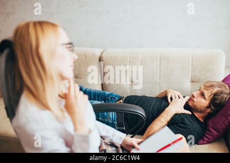 Caucasian male patient lies on a couch in a psychologist office - psychological consultation - treatment for alcoholism and drug addiction Stock Photo