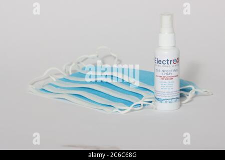 5, blue disposable masks on a white background with a small spray bottle of sanitiser Stock Photo