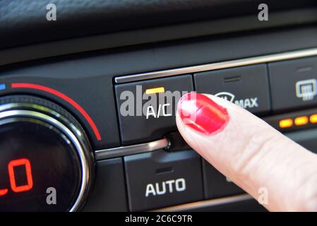 Close up of woman hand pressing turn on air-conditioner button a car Stock Photo