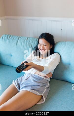 Asian teenage girl sitting laugh watch television Stock Photo