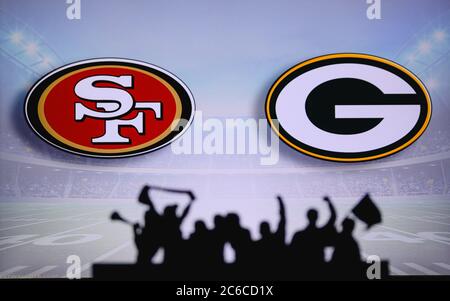 San Francisco 49ers vs. Green Bay Packers. Fans support on NFL Game. Silhouette of supporters, big screen with two rivals in background. Stock Photo