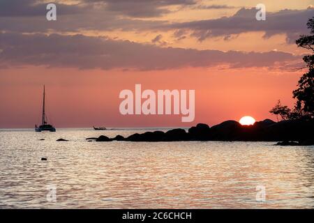 Sun setting behind the silhouette of a rock Stock Photo