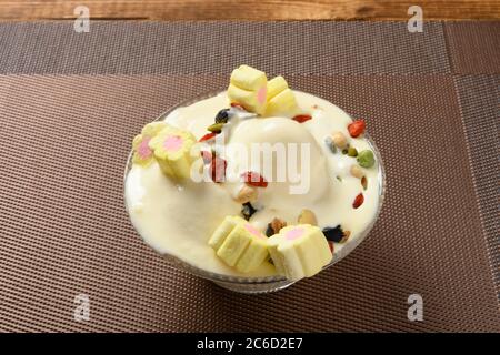 side view bowl of vanilla flavor ice cream sundae in a melting process with marshmallows and various nuts Stock Photo