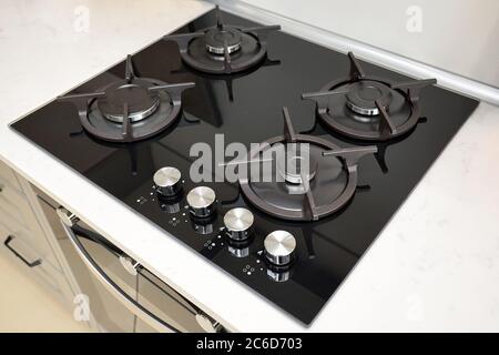 Hob cooker oven made of glass cast iron grill stainless steel control knobs selective focus over out of focus oven, with burner on countertop made of Stock Photo