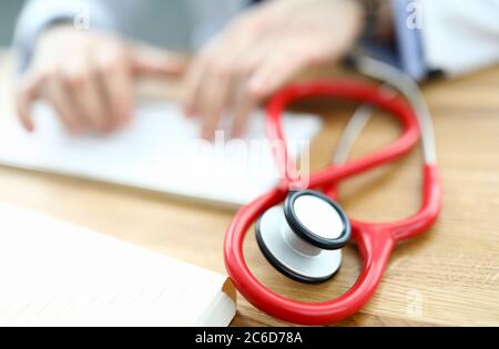 Red stethoscope is lying on table Stock Photo