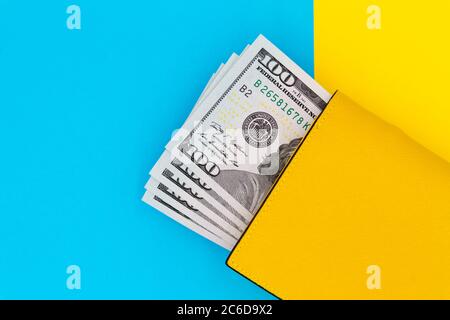 Close-up of yellow wallet with 100 dollar banknotes on a colored background Stock Photo