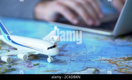 Airplane model closeup, defocused person booking flight tickets online on laptop Stock Photo