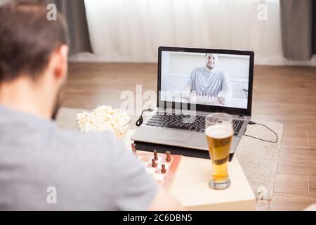 Intelligence friends playing chess on video call during covid-19. Stock Photo
