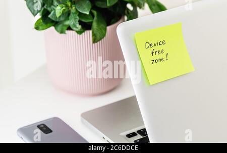 '' Device free zone '' written on green sticky note at laptop Stock Photo