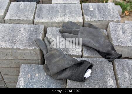 A large pile of stacked concrete pavement slabs and workers' gloves left on them. Stock Photo