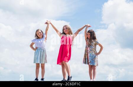 we are strong. sisterhood and friendship. family bonding time. best friends forever. three sisters on sky background. happy childhood. summer vacation. small girls hold hands. love and support. Stock Photo