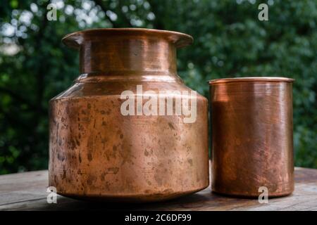 A copper water holder and a glass. In Indian ayurvedic culture it has been established that drinking water out of a copper utensil has many health ben Stock Photo