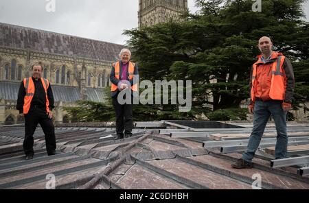 The Rt Rev Nicholas Holtam, Bishop of Salisbury (centre), alongside Robert Titley, Canon treasurer of Salisbury Cathedral (left) and Thomas Burnett, a Director of Salisbury Community Energy (right)as they stand on the roof of Salisbury Cathedral's south cloister as new solar panels are installed as part of the cathedral's plans to be carbon neutral. Stock Photo