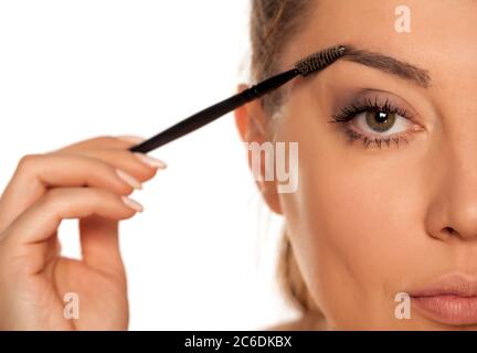 Young woman contouring her eyebrows with dry brush on white background Stock Photo