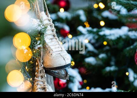 At home, decorated with Christmas decorations, a pair of skates hung. Defocused Christmas tree in the background - image Stock Photo