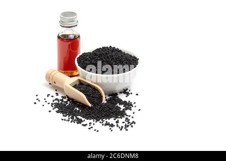 Black cumin seeds in bowl and essential oil in glass bottle. Nigella sativa isolated on white background. Stock Photo