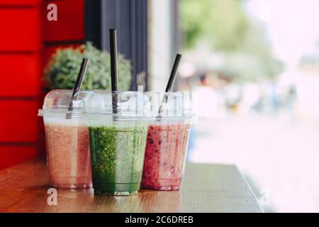 Sweet Smoothie In Plastic Cups On Wooden Table Stock Photo, Picture and  Royalty Free Image. Image 127579885.