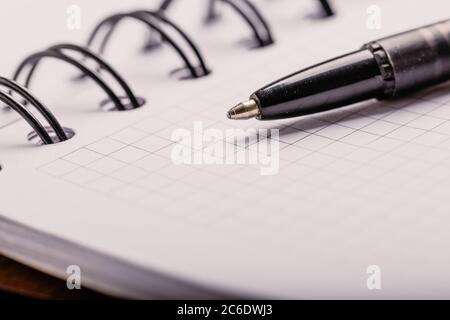 Opened notepad in a cage with an automatic plastic ballpoint pen close-up. Stock Photo