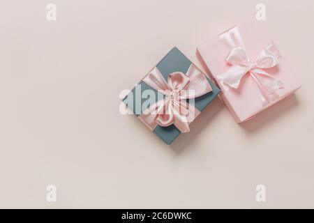 beautiful gift boxes wrapped in paper with gold and pink ribbon on a beige surface. Top view with copy space. Stock Photo