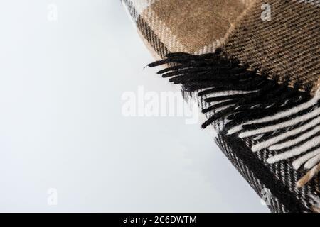 Folded plaid blanket with geometric pattern with ends on a white desk. Empty space for copy. Brown folds corner for lifestyle purposes. Soft wool Stock Photo