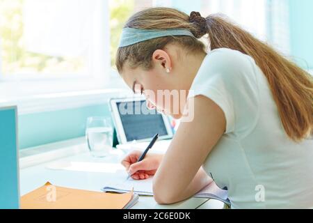 Focused girl doing homework at desk Stock Photo