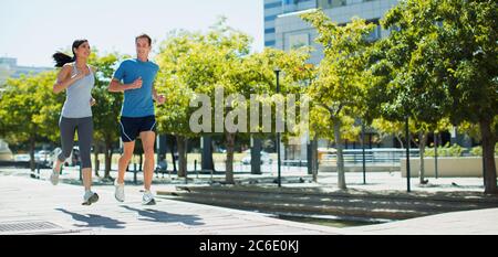 Couple jogging on urban sidewalk Stock Photo