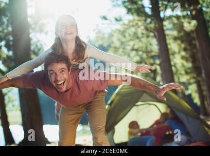 Exuberant father carrying daughter on back in woods Stock Photo