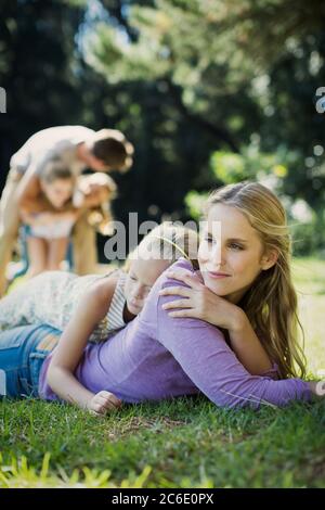 Serene mother and daughter laying in grass Stock Photo