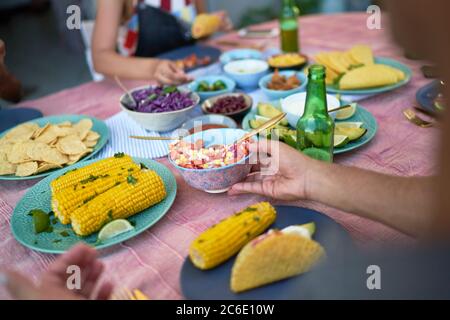 Friends eating tacos and corn at patio table Stock Photo