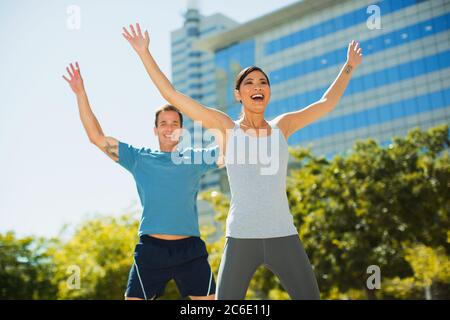 Enthusiastic couple exercising in urban park Stock Photo