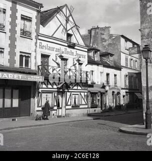 1950s, historical, Montmartre and the cobbled street of Rue du Mont-Cenis, showing the Restaurant du Moulin Joyeux, Paris, France. Located on a hill in the city, the charming french village is known for its artistic history and the Basilica of the Sacre-Coeur, the famous catholic church. Stock Photo