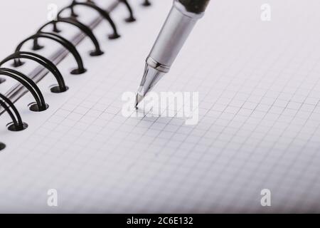 Opened notepad in a cage with an automatic plastic ballpoint pen close-up. Stock Photo