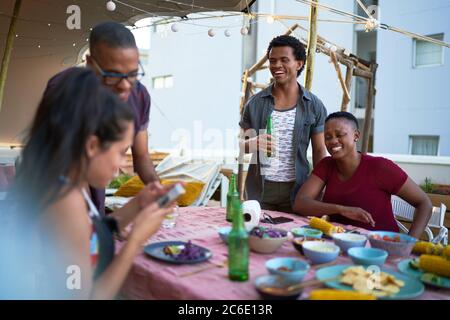 Happy young friends enjoying dinner on rooftop balcony Stock Photo