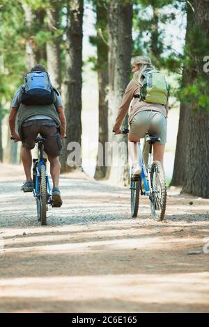 Couple mountain biking with backpacks in woods Stock Photo