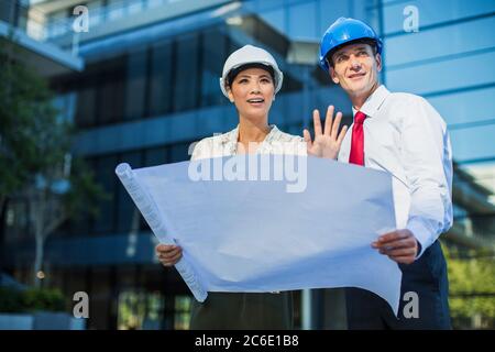 Architects reviewing blueprints outside urban building Stock Photo