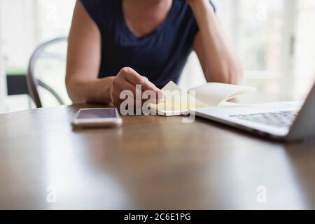 Woman with notebook working from home at laptop Stock Photo