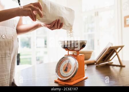 Woman measuring flour for baking in kitchen Stock Photo