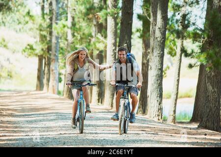 Smiling couple mountain biking in woods Stock Photo