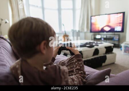 Boy playing video game on living room sofa Stock Photo