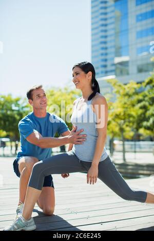 Personal trainer guiding woman with lunges in urban park Stock Photo
