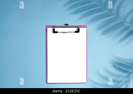 blank empty clipboard with palm shadows on blue background. mockup Stock Photo