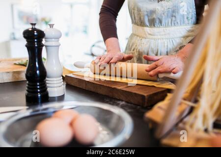 Woman rolling dough with rolling pin in kitchen Stock Photo