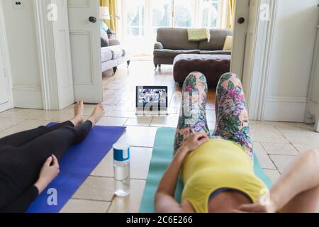 Women practicing yoga online with laptop at home Stock Photo