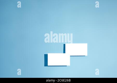 two white empty blank business cards mockup on blue background. top view Stock Photo