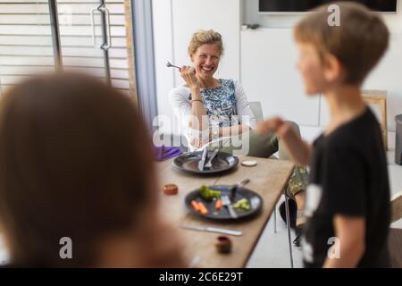 Happy mother and sons eating lunch at home Stock Photo
