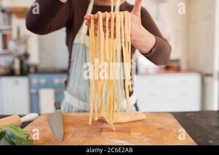Close up woman making fresh homemade pasta in kitchen Stock Photo